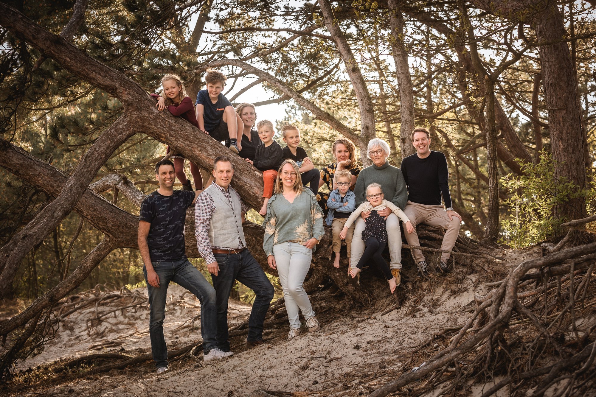 Grote familiegroep bij een omgevallen boomstam in de duinen